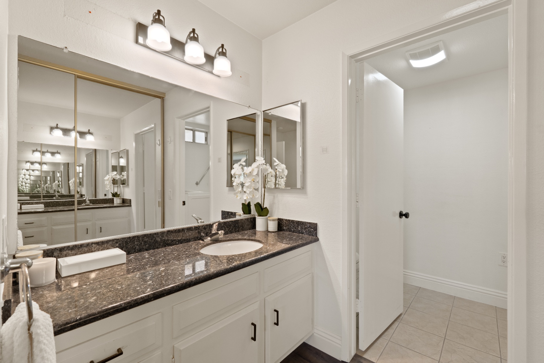 Primary bathroom vanity with granite counter and large mirror