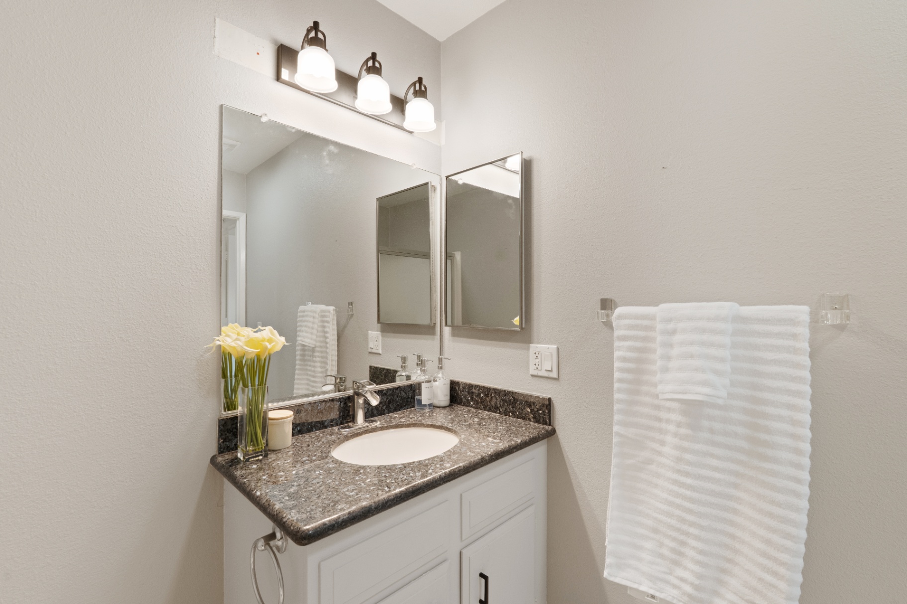 Guest bathroom vanity with granite counter and framed mirror