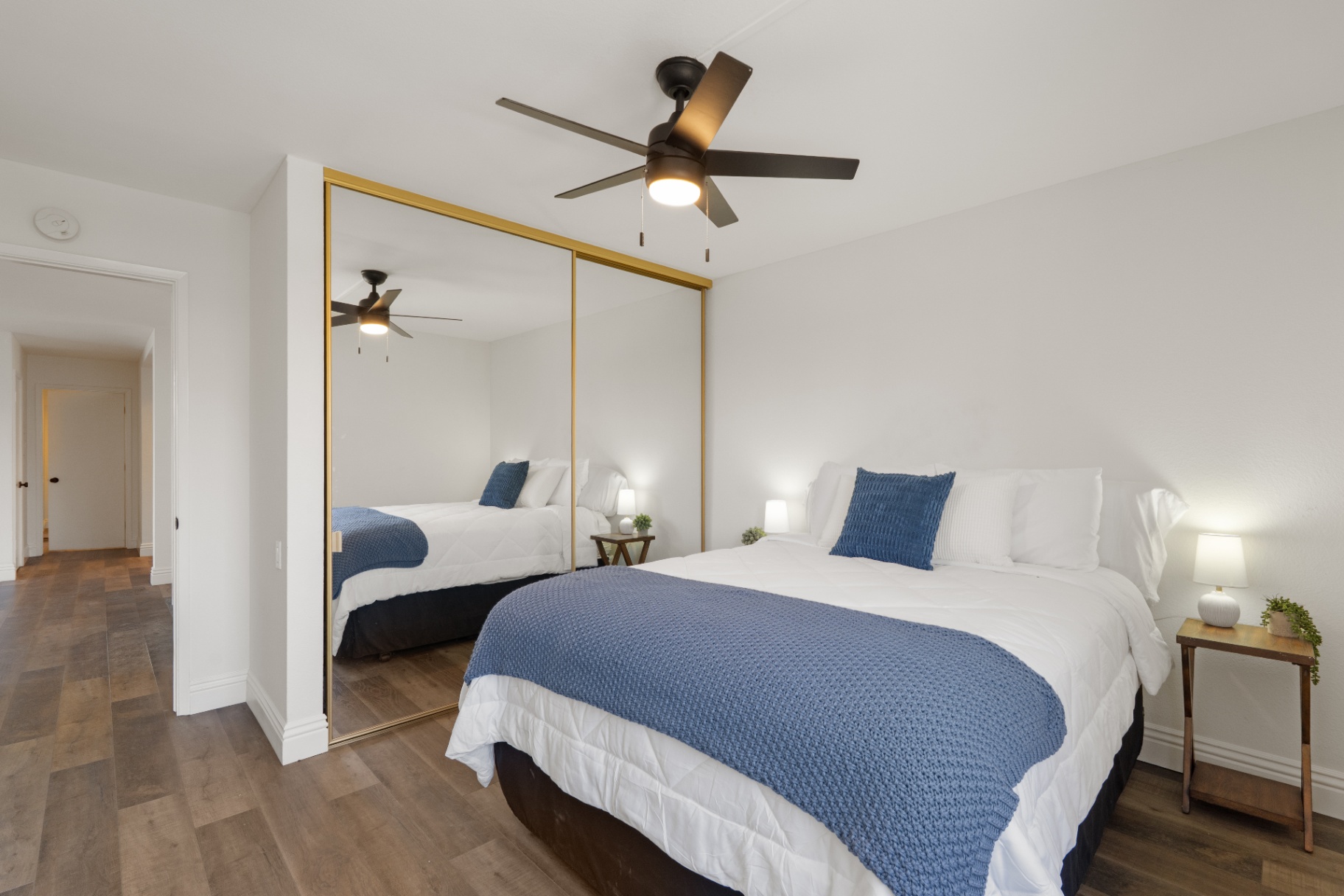 Primary bedroom with wall of mirrored closet doors and ceiling fan