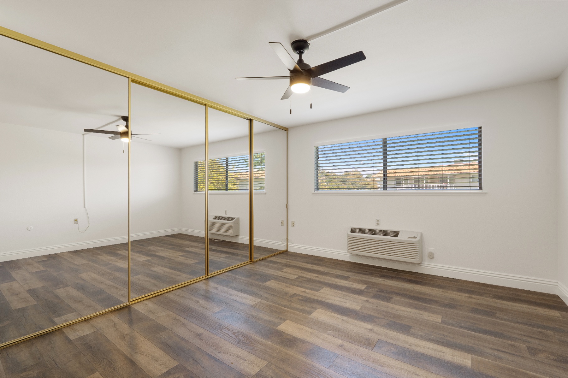 Second bedroom with full wall of mirrored closets and neighborhood window