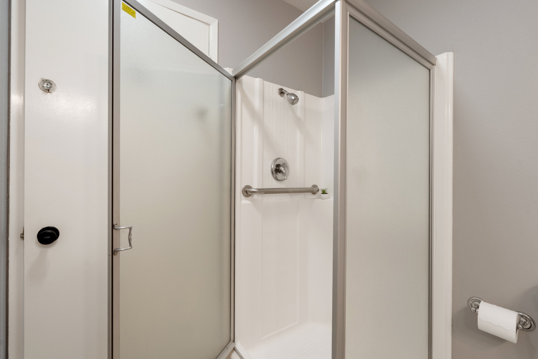 Guest bathroom step-in shower with frosted glass enclosure and grab bar