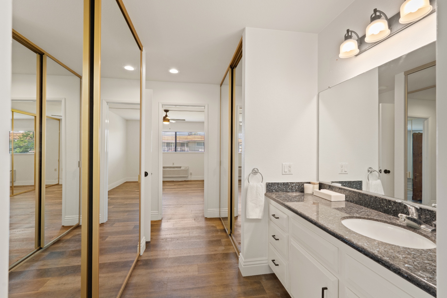 Primary bathroom vanity opening to bedroom with mirrored closets